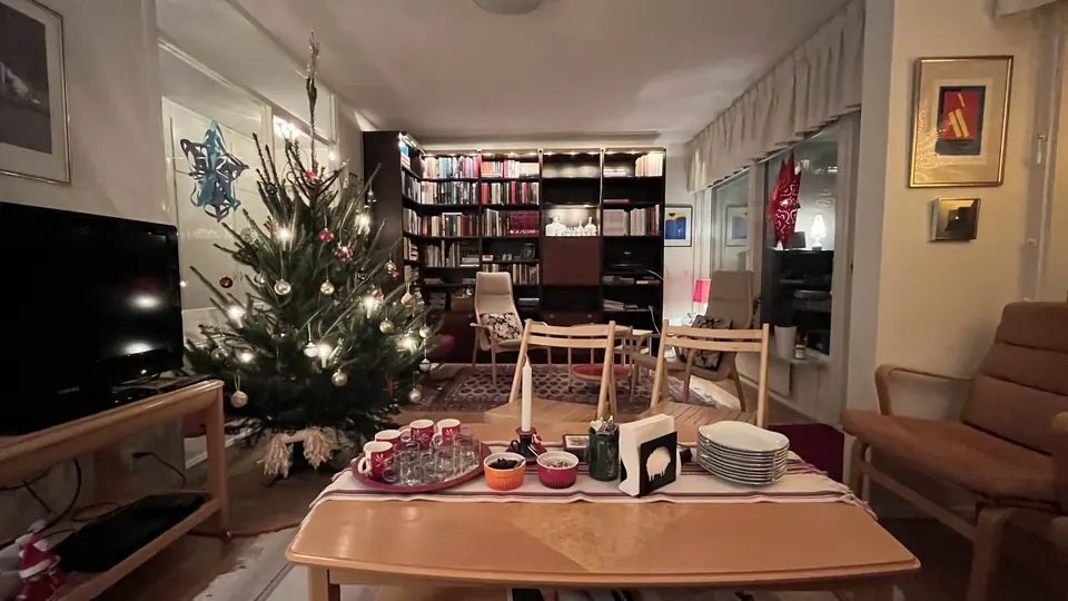 Pyntet juletre med lys i en svensk stue, ved siden av et salongbord med gløggkopper