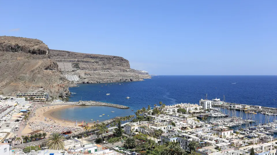 Utsikt over Puerto de Mogán på Gran Canaria med sandstrand, hvite hus, båthavn og klipper mot havet