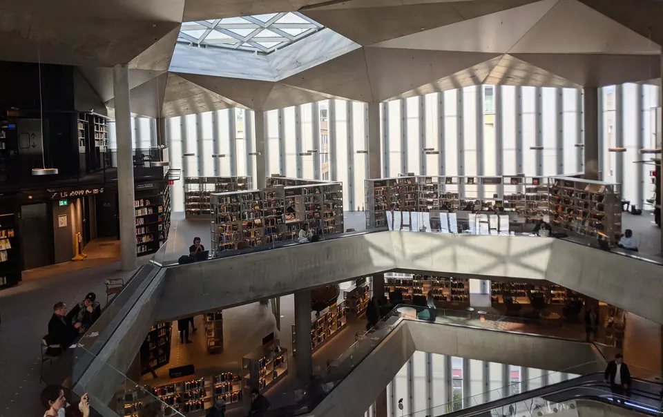 Lyst bibliotek over flere etasjer med bokhyller, lesesteder og takvindu i Deichman Bjørvika i Oslo